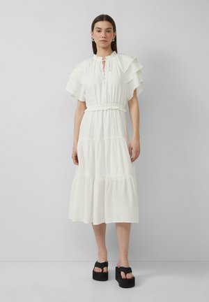 Witte gelaagde jurk met ruffle-mouwen, elastische tailleband en een keyhole-halslijn. Gekoord met zwarte platform sandaaltjes. Effen, lichtgewicht stof.