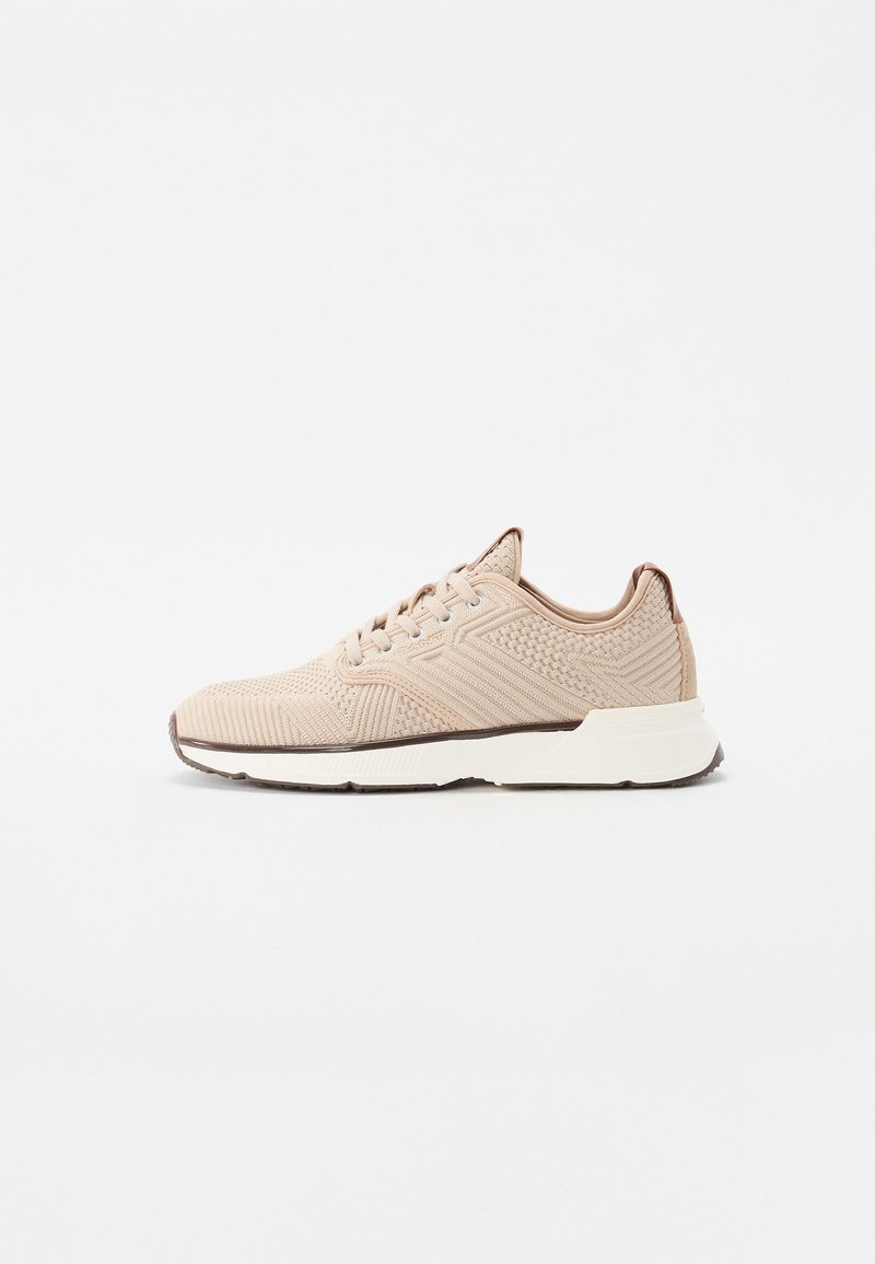 Beige sportssko med en struktureret strikoverdel, rund tå og kontrastfyldt hvid sål. Udstyret med flade snørebånd og minimalistiske design accenter.