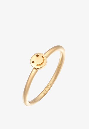 Goldfarbener Metallring mit einem glatten Band und einer runden Fläche, die ein lächelndes Emoji-Design zeigt, das eine polierte Textur und eine einfache Form betont.