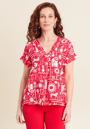 Top rouge à manches courtes avec un décolleté en V et des motifs graphiques blancs, comprenant de la flore, de la faune et des formes abstraites sur un tissu lisse.