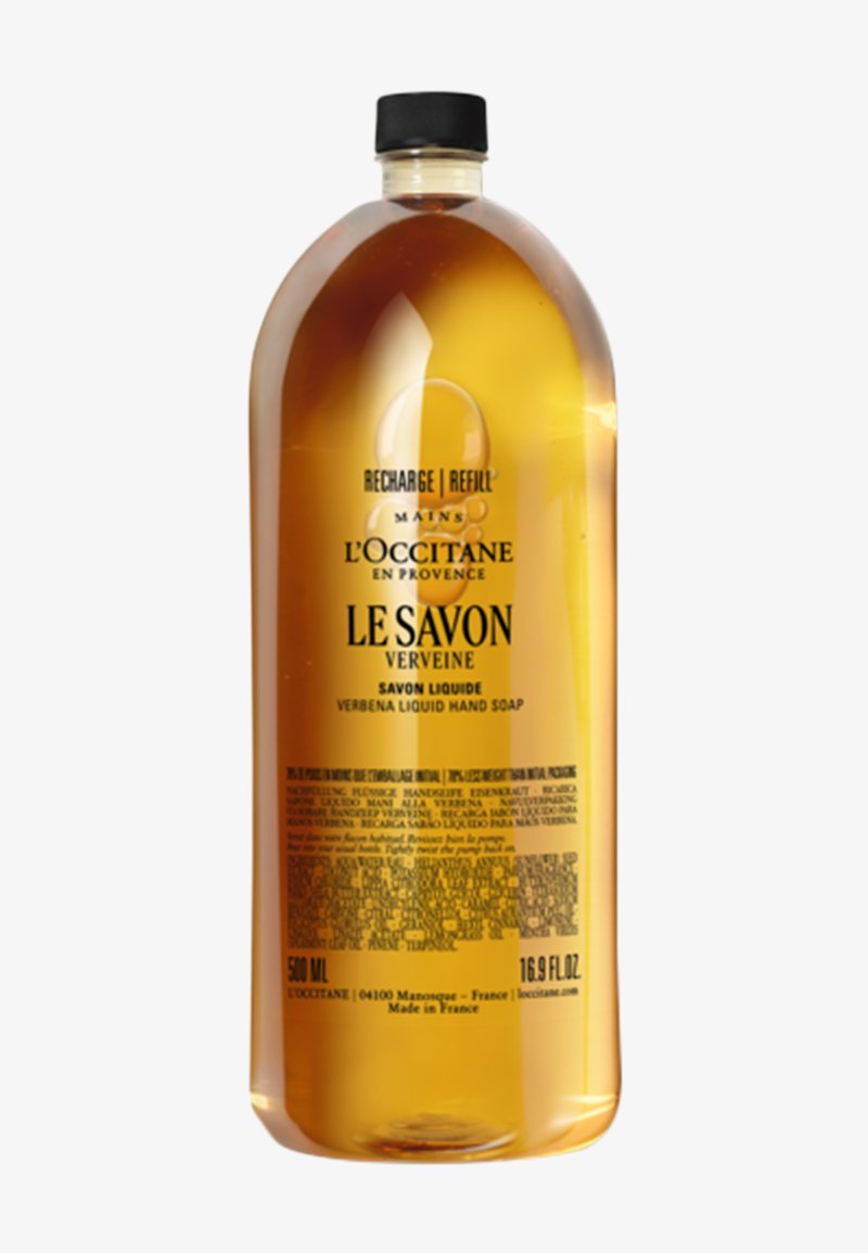 Gennemsigtig flaske med flydende håndsæbe, ravfarvet, 500 ml. Sort låg, markante sorte og gule etiketter med tekst på flere sprog.