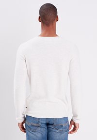 Hellgraues Langarmshirt mit Rundhalsausschnitt, aus weichem Stoff gefertigt. Verfügt über eine dezente Textur und ein kleines Logodetail am Saum.