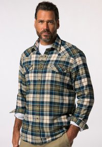 Geruite flanellen shirt in groen, marineblauw en roomkleurig met twee borstzakken. Voorzien van knoopsluiting, lange mouwen opgerold tot de ellebogen en een zachte textuur.