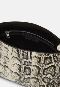 Borsa a tracolla stampa pelle di serpente, beige e nera, con una texture liscia, chiusura a zip in argento e un interno foderato in tessuto nero.