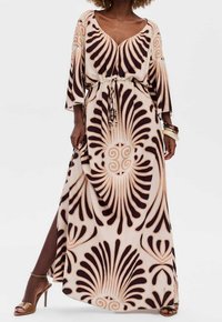 Vestido largo de tela crema con grandes patrones en espiral marrón. Presenta un escote en V profundo, mangas holgadas y una cintura con cordón elástico.