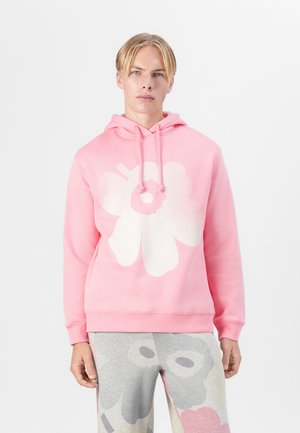 Pink hooded sweatshirt with a large white flower graphic. Soft material, long sleeves, and drawstring hood. Paired with patterned gray pants.