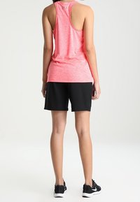 Sleeveless, heathered pink athletic tank top with racerback design, paired with black shorts. Features lightweight, breathable fabric.
