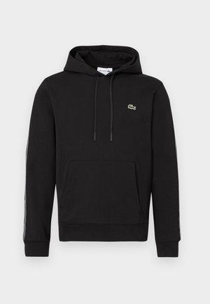 Sudadera negra con capucha, bolsillo frontal, cordones y pequeño logo de cocodrilo verde en el lado izquierdo del pecho, con franjas de la marca en las mangas.