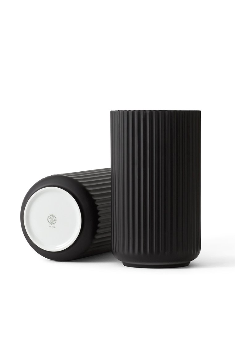 Schwarze Keramikvase mit vertikaler, gerippter Textur, zylindrischer Form und einem glatten, weißen Sockel mit einem Logo auf der Unterseite.