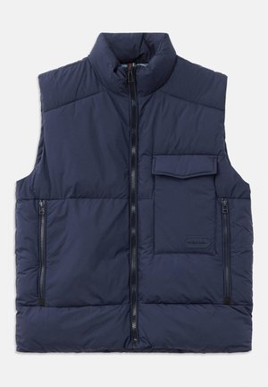 Chaleco acolchado azul marino con cuello alto, cierre frontal de cremallera, dos bolsillos laterales con cremallera y un bolsillo de solapa en el pecho. Textura suave.