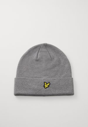 Bonnet en tricot gris avec un ourlet replié, présentant un logo d'oiseau brodé noir et jaune à l'avant. Texture douce et forme épurée.