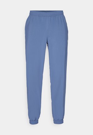 Blå, lette joggebukser med elastisk liv og mansjetter. Har en jevn tekstur og en liten logo på siden.