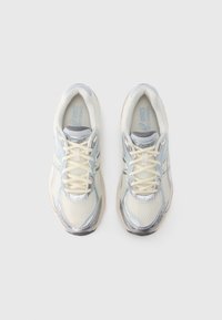 Lekki buty sportowe z siateczkową cholewką w kremowych i niebieskich odcieniach, z metalicznymi srebrnymi akcentami i sznurowaniem.