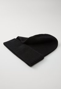 Black ribbed knit beanie with a folded cuff. The texture is soft, featuring vertical lines throughout the material.