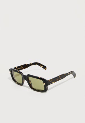 Lunettes de soleil rectangulaires à motif écaille de tortue avec des verres teintés vert foncé et des branches épaisses sur un fond clair uni.