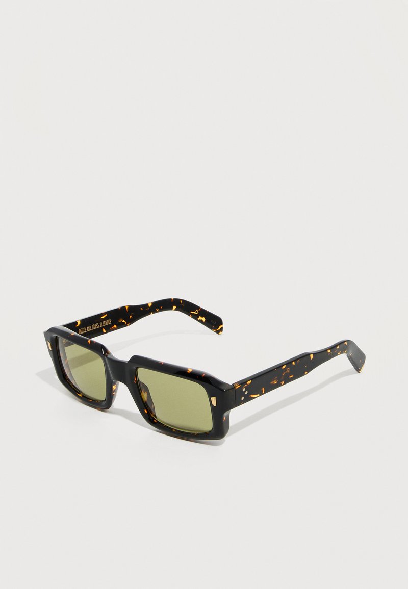 Ορθογώνια γυαλιά ηλίου με σχέδιο χέλυος χελώνας, φακούς με σκούρο πράσινο χρώμα και χοντρές μπράτσες, σε απλό ανοιχτό φόντο.