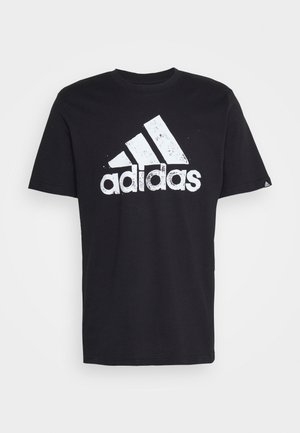 Czarna koszulka z krótkim rękawem z wyblakłym białym logo Adidas i napisem na środku klatki piersiowej.