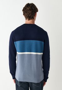 Férfi kötött pulóver kerek nyakkal, hosszú ujjakkal, és vízszintes csíkokkal tengerészkék, türkkiz, fehér és világosszürke színekben. Simább tapintású anyag.