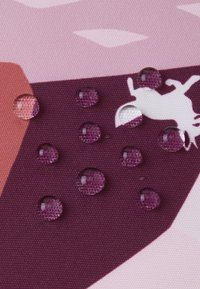 Teksturowana tkanina w odcieniach różu i fioletu z kroplami wody na powierzchni, pokazująca gładki połysk i złożone szczegóły wzoru.