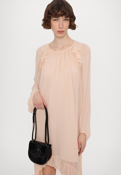 Lys ferskenfarvet chiffon kjole med flæsedetaljer, lange ærmer og asymmetrisk kant. Sort håndtaske med en struktureret design og rem.
