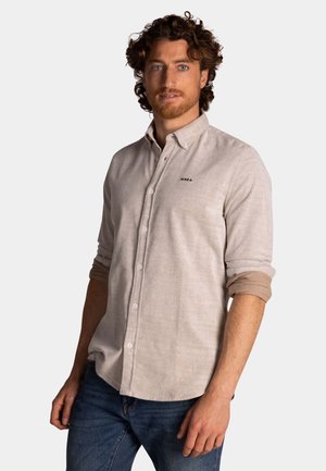 Lichtbeige overhemddshirt met een kraag, lange mouwen en opgerolde mouwen. Bevat een klein zwart logo op de borst. Textuurstof.