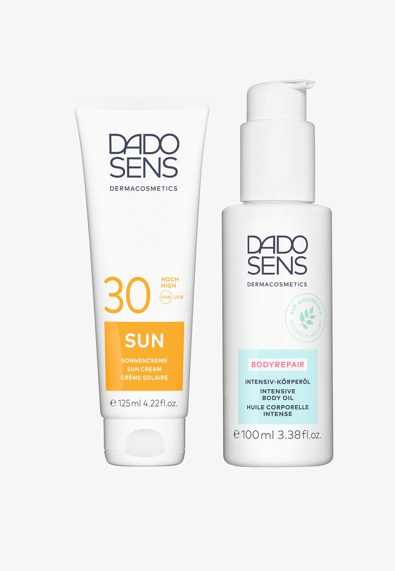 Two DADO SENS products: a white tube of sun cream with orange accents, labeled "30 SUN," and a white bottle of body oil with a blue label.