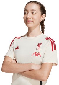 Maillot de football crème avec des accents rouges. Comprend le logo L.F.C. et le branding AXA. Possède des épaules à rayures rouges et un col rond. Matière en mélange de coton.