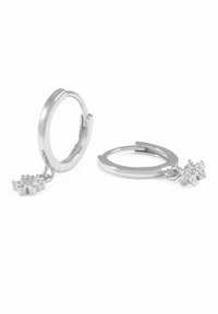 Silverfärgade hoopörhängen med en slät yta och en blomstermönstrad charm prydd med små klara stenar, med hängande design.