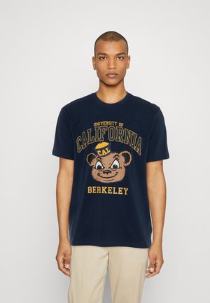 Námořnická bavlněná tričko s grafikou medvěda s kšiltem a textem "Univerzita Kalifornie Berkeley" v žluté barvě. Krátké rukávy.