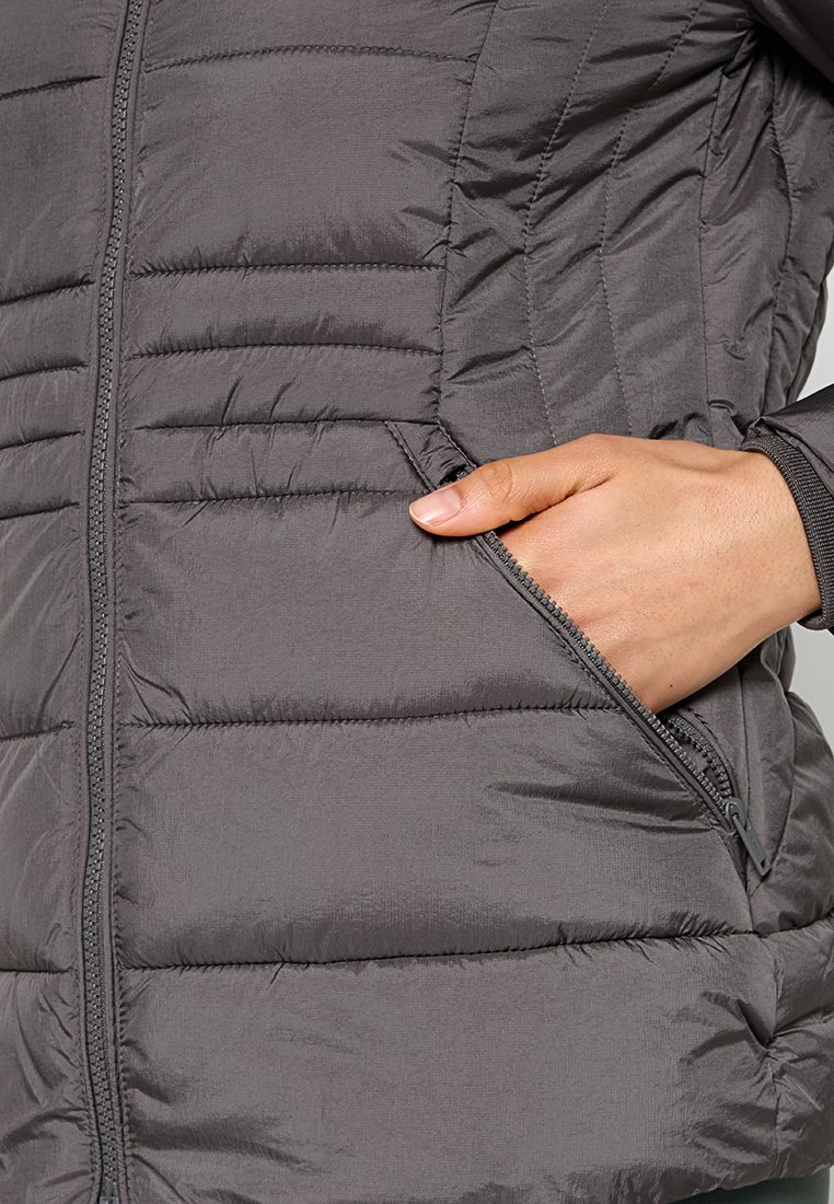 La giacca puffer grigia presenta sezioni trapuntate, tasche con zip e una chiusura frontale con zip. Il materiale sembra leggero e liscio.