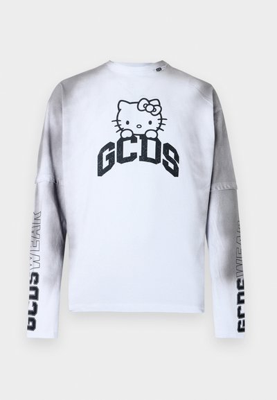Valkoinen pitkähihainen paita, jossa harmaasävyiset hihat, musta "GCDS" teksti, Hello Kitty -grafiikka rinnassa ja "GCDS WEAR" teksti hihoissa.