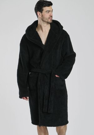Zwarte badjas met capuchon, gemaakt van zachte, gestructureerde stof. Voorzien van een strikriem, voorzakken en een losse, comfortabele pasvorm die tot halverwege de bovenbenen valt.