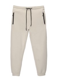 Helle beige Sweatpants aus weichem Material, mit einem elastischen Bund mit Kordelzug, zwei Reißverschlusstaschen und einem schmal zulaufenden Bein Design.