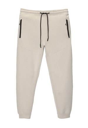 Pantaloni de trening de culoare bej deschis, dintr-un material moale, cu o talie ajustabilă prin șnur, două buzunare cu fermoar și un design cu picior tapered.