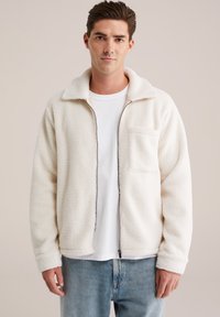 Jachetă din fetru alb cu închidere cu fermoar, guler �și buzunar frontal. Purtați-o peste un tricou alb, asociată cu blugi de culoare albastră deschisă. Textură moale.
