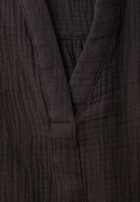 Tissu coton noir texturé avec coutures visibles et détail de couture en forme de col en V.