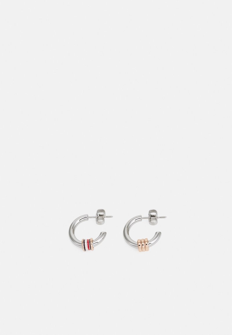 Paire de petites boucles d’oreilles créoles en argent avec trois anneaux en or rose sur chacune, présentées sur un fond gris clair uni.