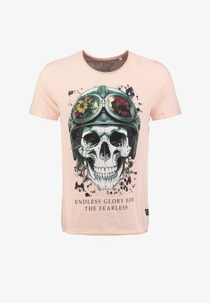 Hellrosa T-Shirt aus Baumwolle mit einem Totenkopf-Design, grünen Schutzbrillen und floralen Akzenten. Der Text lautet "ENDLOSE EHRFURCHT FÜR DIE FÜRCHTLOSEN."