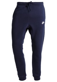 Pantalones de chándal azul marino con cintura elástica y cordón, que presentan un pequeño logo blanco de Nike en el muslo izquierdo. Textura de tela suave.