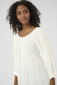 Weiße, strukturierte Bluse mit einem Rundhalsausschnitt, dreiviertelärmel und einem Knopfdetail an der Vorderseite, die sanft um den Körper fällt.