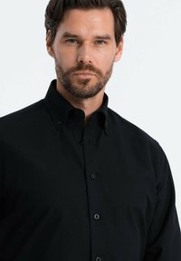 Camicia nera con bottoni, realizzata in un tessuto morbido, caratterizzata da un colletto classico, una texture sottile e bottoni scuri lungo la patta.