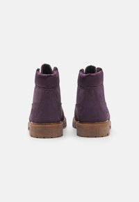 Fioletowe, zamszowe botki za kostkę z okrągłym noskiem, wyściółką oraz gumową podeszwą. Posiadają detale stębnowania i gładką teksturę.