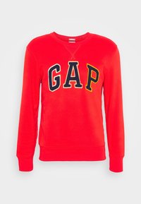 Felpa rossa a maniche lunghe con collo rotondo e lettere "GAP" in nero e giallo ricamate sul petto, su uno sfondo neutro.