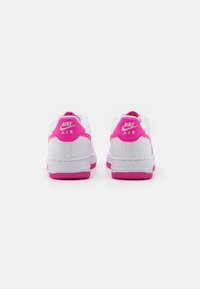 Nike Air tossut, joissa on valkoinen nahkatoppi, vaaleanpunaiset yksityiskohdat kantapäässä ja pohjassa, teksturoitu kuminen pohja sekä brodeeratut logoyksityiskohdat.