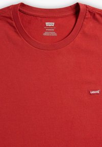 Camiseta de algodón roja con cuello redondo y mangas cortas. Presenta un pequeño logo de Levi's en blanco y rojo en el pecho izquierdo. Textura suave.
