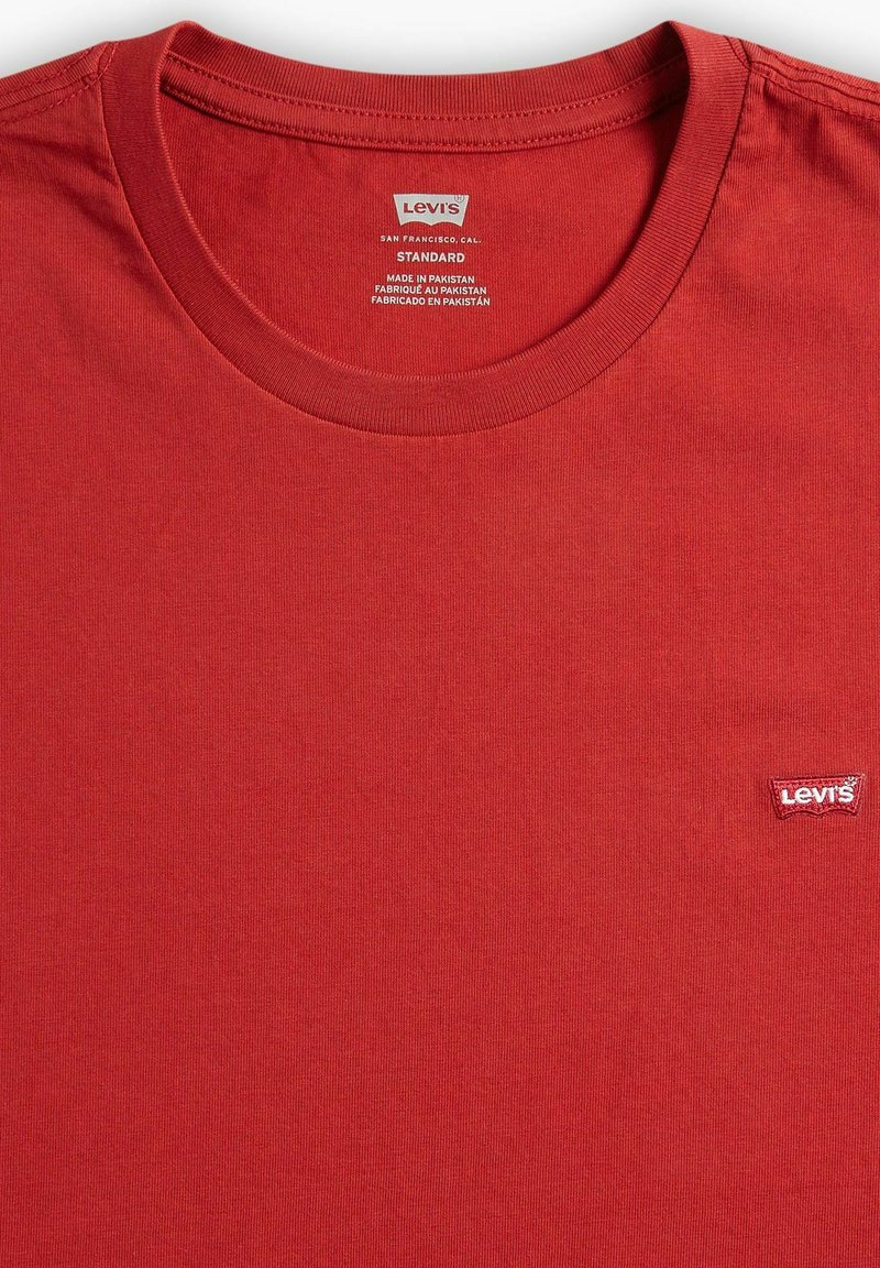 T-shirt in cotone rosso con scollo rotondo e maniche corte. Presenta un piccolo logo bianco e rosso di Levi's sul lato sinistro del petto. Texture liscia.