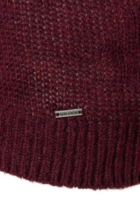 Knitted burgundy sweater with textured fabric, featuring ribbed hem and a small metal tag branded "MORE & MORE" sewn into the side.