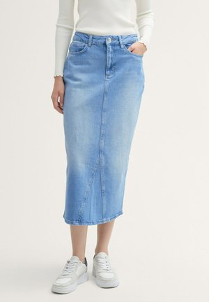 Light blue denim midi skirt with a straight cut, front pocket, and side seam details. Paired with white sneakers.