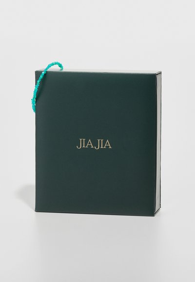 Scatola regalo verde scuro con un logo in oro impresso "JIA JIA" e un manico di perline turchesi. Superficie liscia con bordi netti.