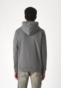 Grijze hoodie met een ontspannen pasvorm, voorzien van een trekkoord in de capuchon en een geribbeld uiteinde. Zachte stof en eenvoudig design. gedragen met lichtgrijze jeans.